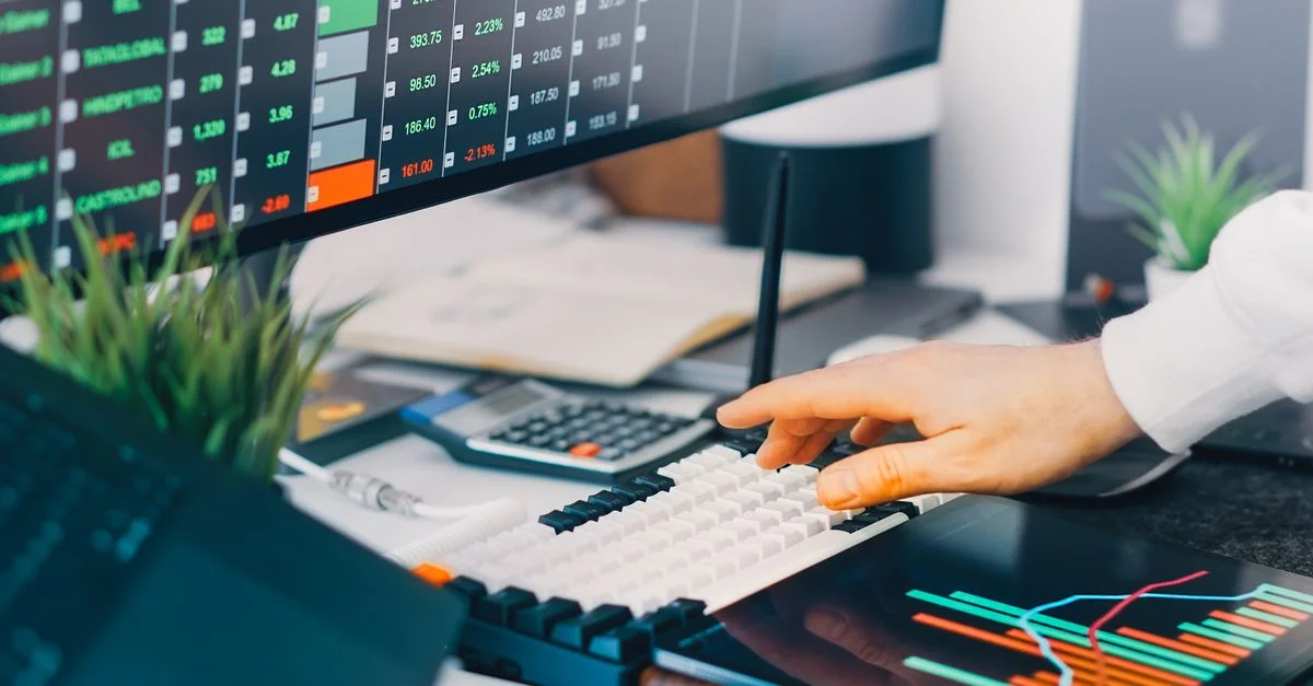Espace de travail professionnel avec des graphiques de trading et des données de marché sur des écrans, idéal pour les contextes de finance et d'investissement.