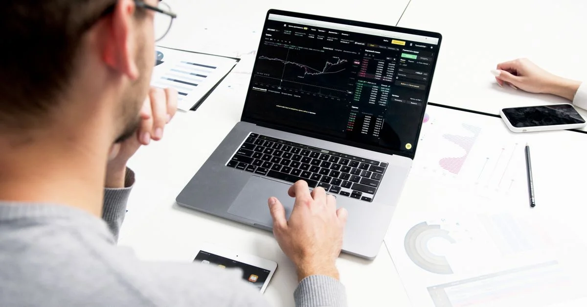 Professionnel des affaires analysant des données boursières sur un ordinateur portable pour des insights d'investissement.