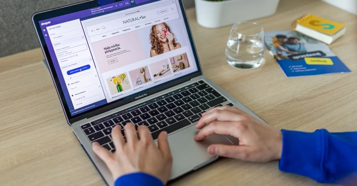 Mains tapant sur un ordinateur portable montrant un site de commerce électronique dans un bureau moderne.