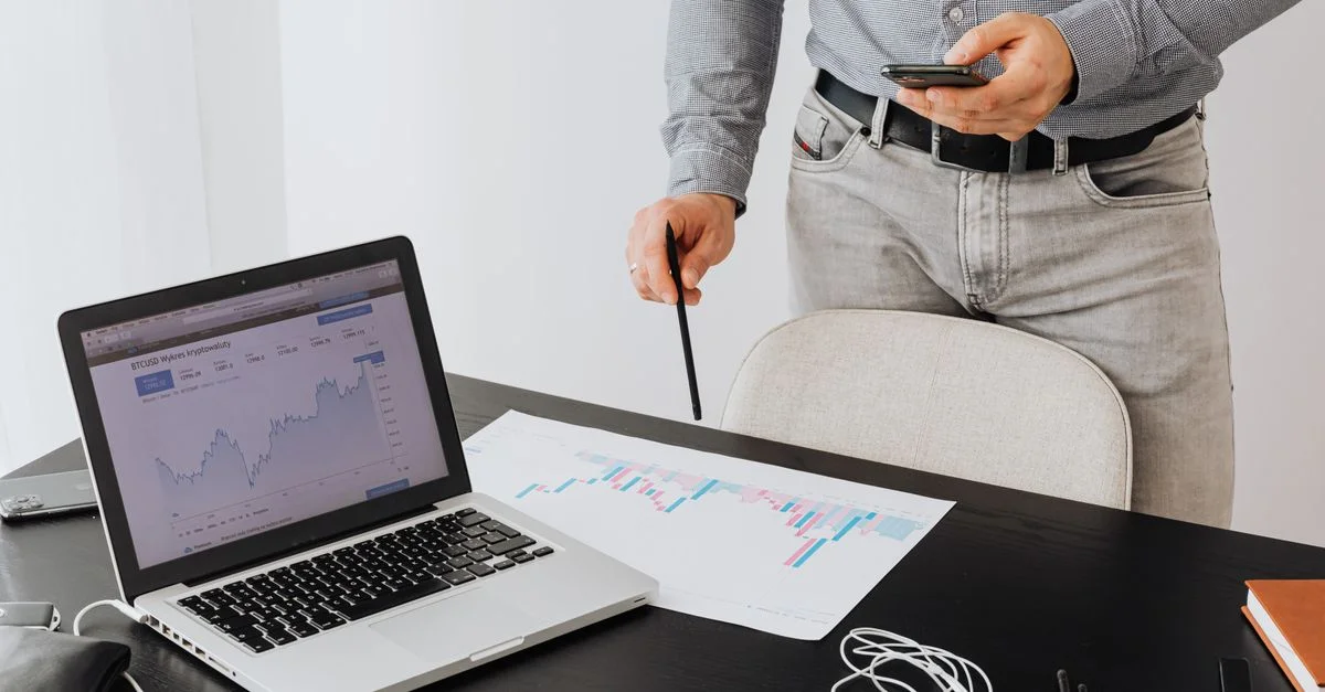 Professionnel des affaires analysant les tendances de la cryptomonnaie sur un ordinateur portable avec des graphiques et des tableaux.